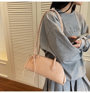 Pale pink baguette bag detail with soft matte leather and bow-tie strap decoration
