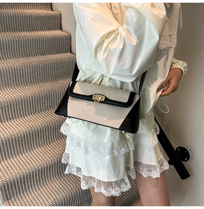 Detail of contrast stitch shoulder bag with gold clasp and beige woven texture