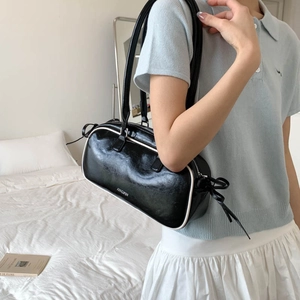 Detail of black underarm bag with white contrast stitching and bow drawstring ornament