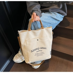 Macro shot of off-white canvas tote bag with brown straps and detailed metal snap pocket