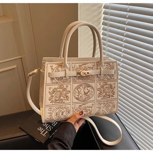 Close-up of beige handbag with intricate floral bird embroidery and metallic buckle