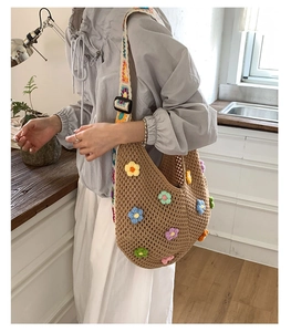 Close-up of woven shoulder bag with colorful crochet flower details and wide strap
