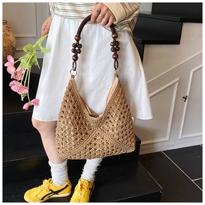 Detail of hand-woven straw hobo tote with vintage wooden bead handles and hollow patterns