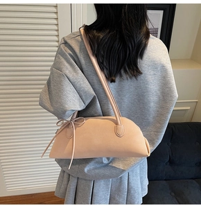 Detail of light pink crescent underarm bag with elegant bow knot and dual handles