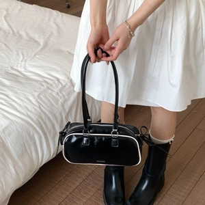 Detail of black bow shoulder bag with white piping and long straps in high-quality wax leather