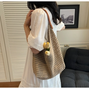 Close-up of beige crochet tote bag with brown leather straps and metal rivets detail