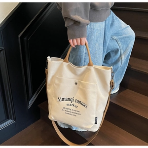 Detail of beige canvas tote bag with brown straps and functional front pocket