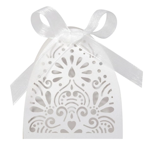 Detail of laser-cut white wedding favor box with heart patterns and organza ribbon
