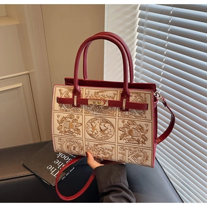 Detail of red and beige embroidered handbag with bird and floral patterns and gold buckle