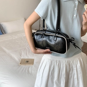Minimalist black bowling bag with white piping details and large storage capacity