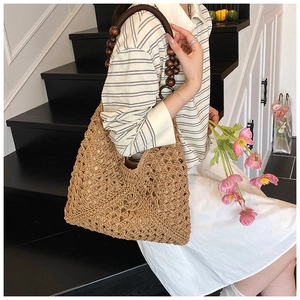 Detail of hand-woven straw tote bag featuring decorative dark brown wooden bead handles