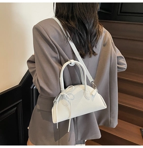 Detail of white half-moon bag with bow knot on grey suit background for urban style