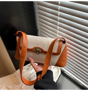 Detail of a white canvas shoulder bag with caramel leather trim and gold buckle lock