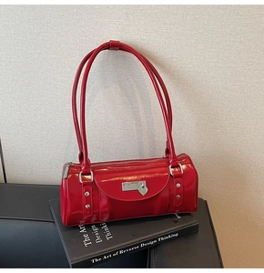 Detail view of red glossy patent leather bowling bag with silver heart charm and metal hardware