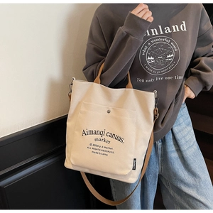 Close-up of beige canvas tote bag showing the front pocket with button and brown strap