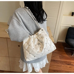 Détail du sac seau blanc matelassé avec bandoulière chaîne et pendentif étoile brillant