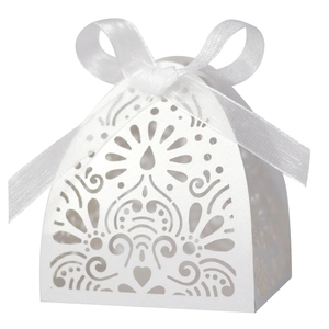 Close-up of white laser-cut wedding favor box with elegant heart pattern and ribbon bow
