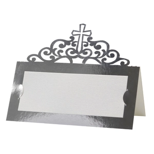 Detail of laser-cut cross and scroll patterns on a silver wedding table place card