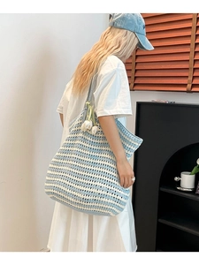 Minimalist blue and white striped crochet tote bag with flower charm on model's shoulder