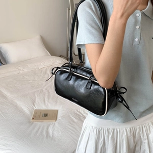Detail showing contrast white piping on black faux leather baguette bag with strap