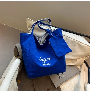 Detailed macro view of the blue nylon tote bag's striped lining and small zip pouch