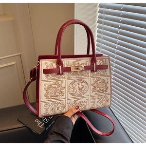 Close-up of bird and floral embroidery on a red and white handbag with buckle lock