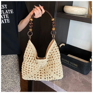 Detail view of beige woven hobo bag with vintage crochet pattern and dark wooden bead handle