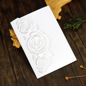 Macro detail of laser-cut rose patterns on white specialty paper wedding invitation