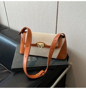 Detail of canvas and leather shoulder bag with gold ring buckle on a business book