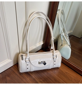Detailed close-up of cream bowling bag with glossy finish and heart lock charm on wood floor