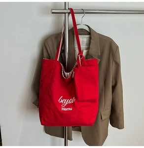 Macro view of red nylon tote bag with striped lining and matching small zipper pouch