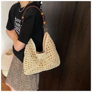 Close-up of woven straw tote bag featuring detailed wooden bead shoulder strap and lining