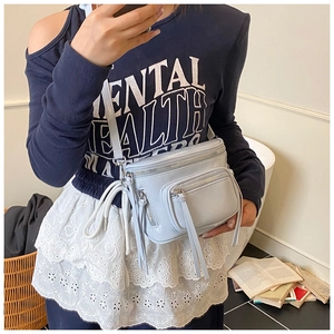 Détail du sac bandoulière bleu clair avec plusieurs poches zippées et breloques à pompons