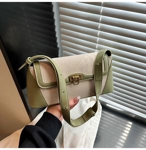 Detail view of the contrasting canvas and olive green leather texture with a gold buckle