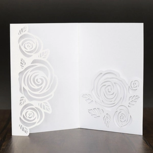 Detail view of laser-cut rose patterns on elegant white wedding invitation card