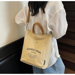 Detail of canvas tote bag with brown straps and functional front snap pocket for storage