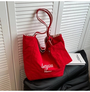 Detail of red canvas tote bag with striped lining and matching zippered pouch on sofa