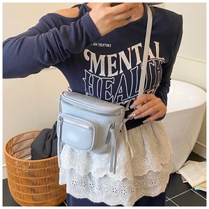 Détail macro d'un sac seau en cuir PU bleu clair avec des fermetures éclair en métal argenté