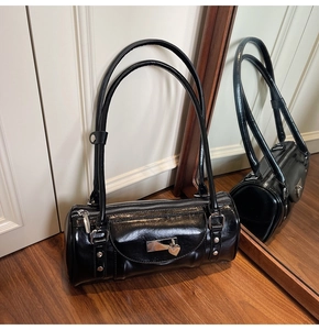 Close-up of a glossy black leather bowling bag with silver lock and heart pendant detail