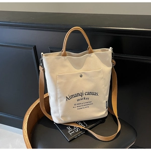 Detailed shot of beige canvas tote bag with brown handles and snap pocket on a black chair