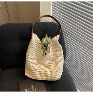 Detail showing cream woven texture and brown leather handle of the beach tote bag