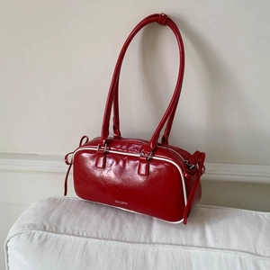 Red glossy patent leather shoulder bag with white piping and decorative side bows