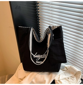 Detail of black canvas tote bag with beyou print and striped ribbon handles