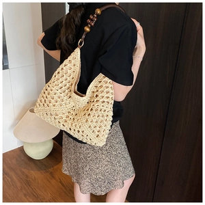 Close-up of beige woven tote with hollow mesh structure and dark wood bead strap detail