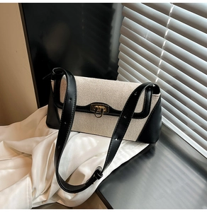 Detail of canvas textured shoulder bag with black leather trim and gold metal clasp