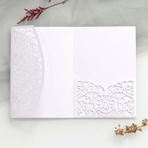 Close-up of white laser-cut vine patterns on elegant wedding invitation cards