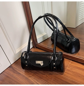 Detail of a shiny black patent leather bowling bag with a silver heart charm and studs