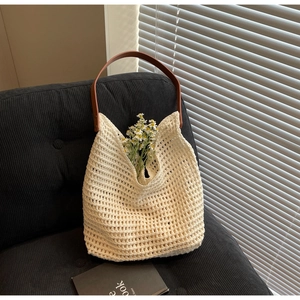 Detail of hollow woven tote bag with brown leather handle and rivet accents
