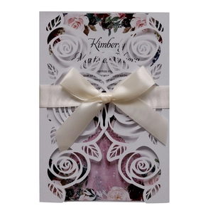 Detailed laser cut rose patterns and satin ribbon bow on a wedding invitation