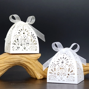 Close-up of laser-cut floral patterns and organza ribbon on ivory wedding favor boxes
